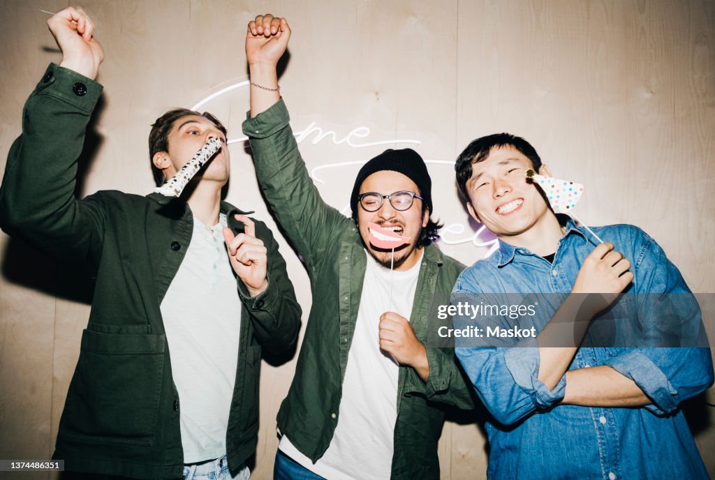 Carefree multiracial male friends with props enjoying in college dorm