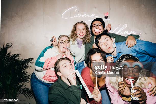 happy multiracial male and female students with props against wall in college dorm - matasuegras fotografías e imágenes de stock