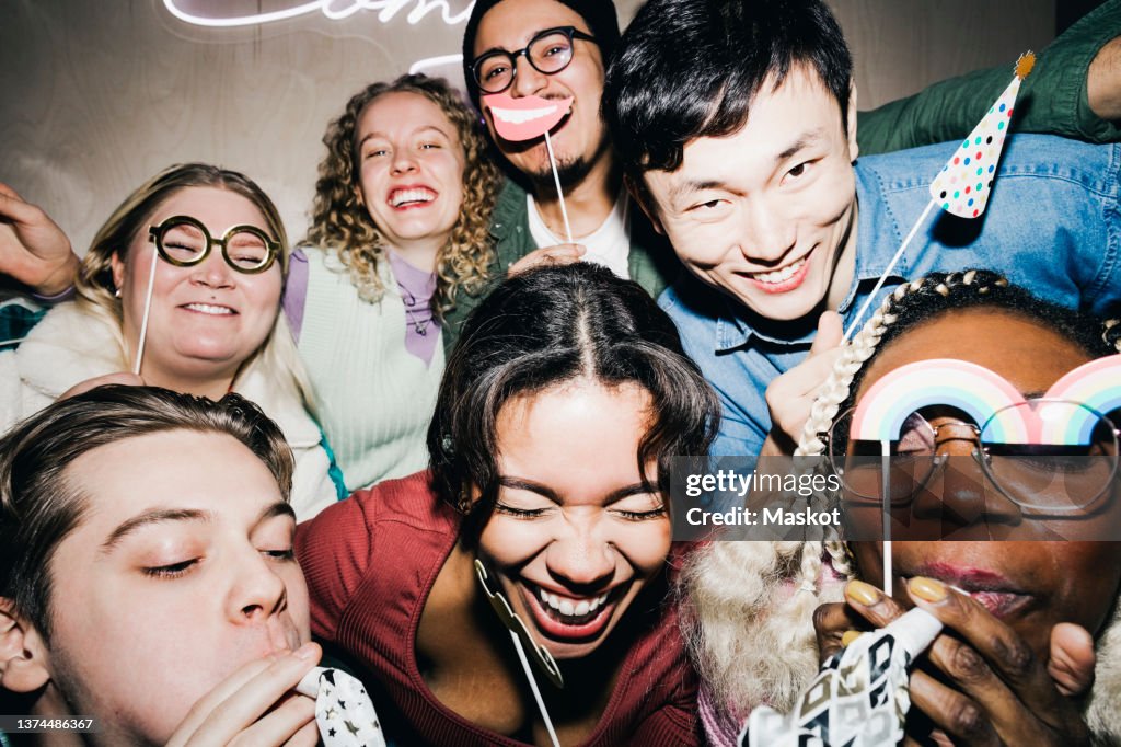 Carefree multiracial roommates with props enjoying in college dorm