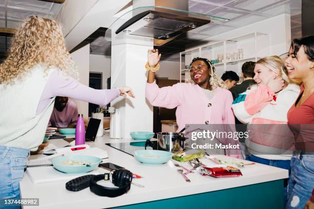 happy multiracial young male and female friends having noodles in college dorm - happy students stockfoto's en -beelden