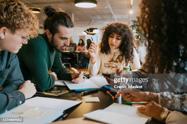 students studying together at table in cafeteria - adult student fotografías e imágenes de stock