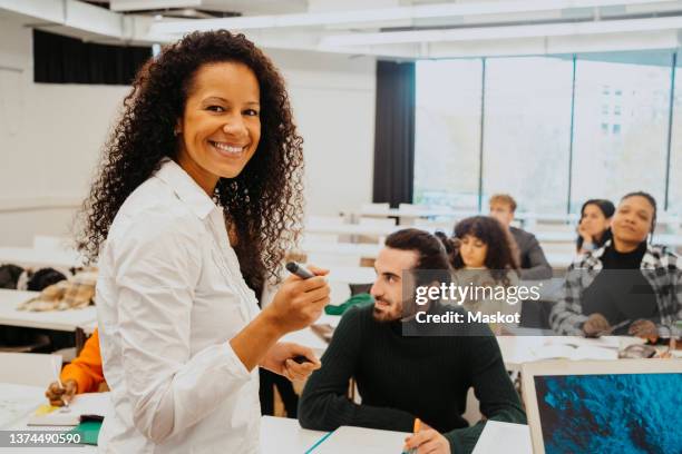 portrait of smiling teacher with university students sitting in classroom - female professor stock pictures, royalty-free photos & images