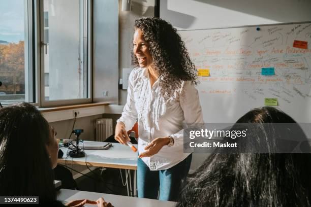 cheerful professor teaching students sitting in classroom at community college - docent stockfoto's en -beelden