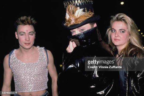 British-Jamaican singer Marilyn, wearing a sparkling crop top, British singer and songwriter Boy George, his face obscured by the collar of his black...