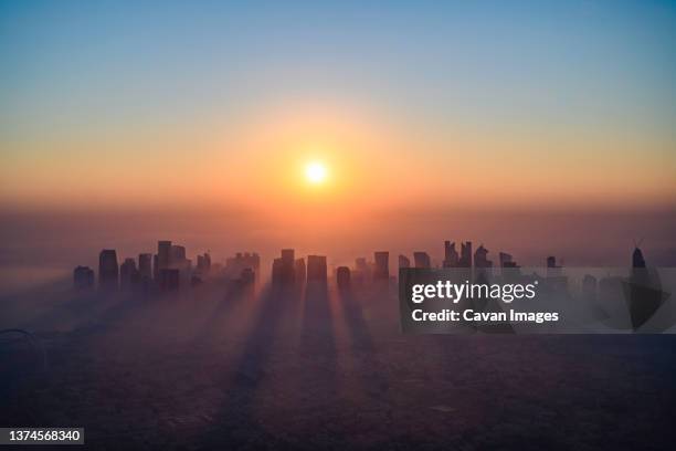 doha skyline at sunrise with morning fog - doha skyline stock-fotos und bilder