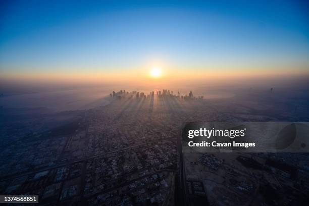 doha skyline at sunrise with morning fog - qatar photos et images de collection