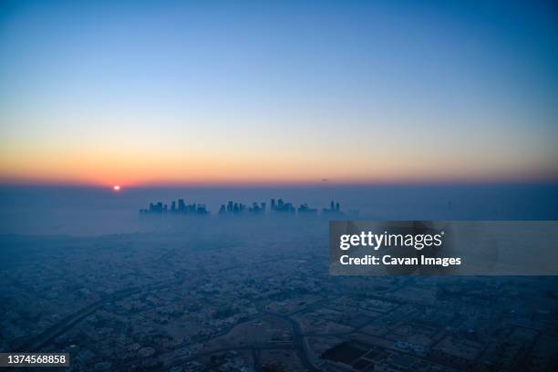 doha skyline at sunrise with morning fog - doha skyline stock-fotos und bilder