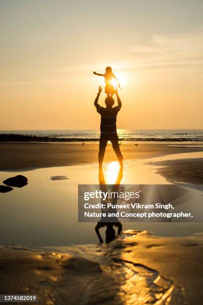 a playful father throwing son in the air at the beach - indian family vacation stock pictures, royalty-free photos & images
