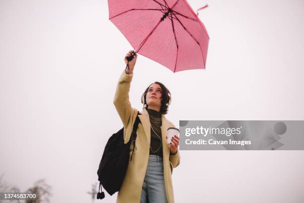 teenage girl with an umbrella walking in city in autumn - chapéu cinzento - fotografias e filmes do acervo