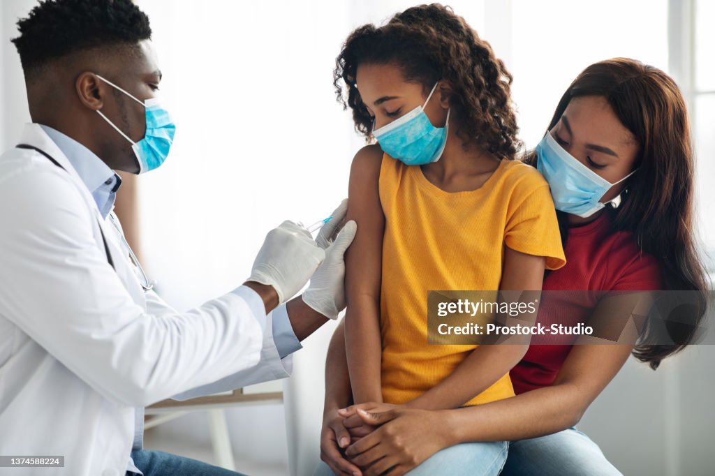 African american doctor making vaccination in shoulder for child