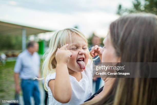 young toddler girl makes crazy silly face at her mother. - trotzanfall stock-fotos und bilder