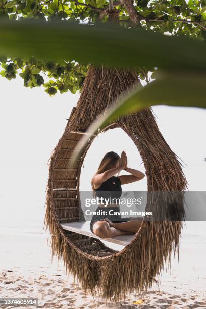 woman doing yoga on bamboo estructure - beach vibes stock-fotos und bilder