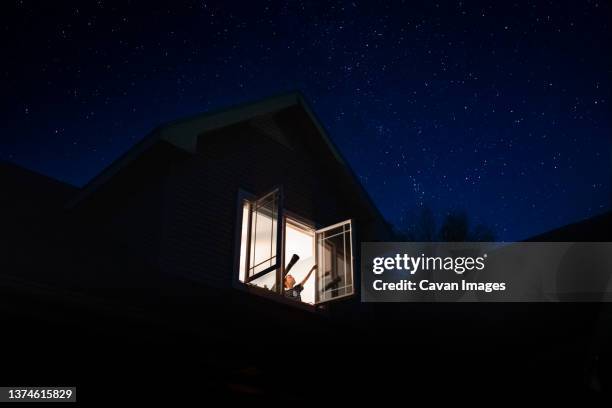 a child pointing to the stars from his bedroom window - mensch fernrohr stock-fotos und bilder