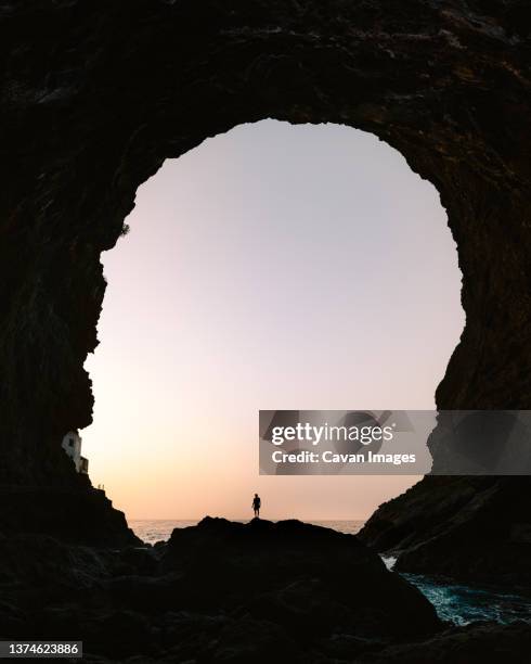 silhouette of a young men in a great cave on la palma - cave stockfoto's en -beelden