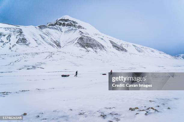 two expedition team members pull up sleighs - north pole fotografías e imágenes de stock