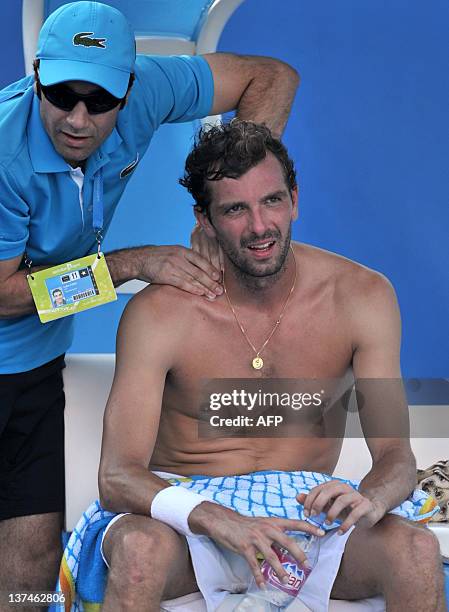 Julien Bennetteau of France gets a message from a trainer during a break in action against Kei Nishikori of Japan in their third round men's singles...