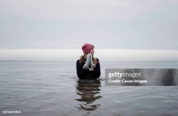 woman peacefully stood cold water swimming in winter - winter strand stock-fotos und bilder
