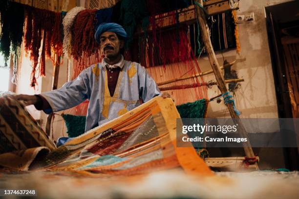 front view of an arab vendor of handmade carpets. - maroc business stock-fotos und bilder