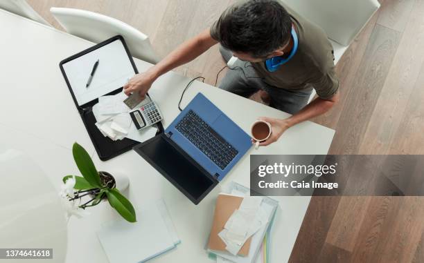 man with receipts paying bills at laptop - calculator top view stock-fotos und bilder