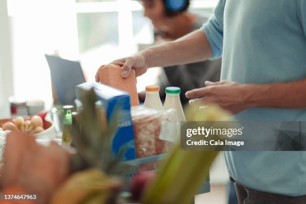 man unloading grocery delivery at kitchen counter - unloading stock pictures, royalty-free photos & images