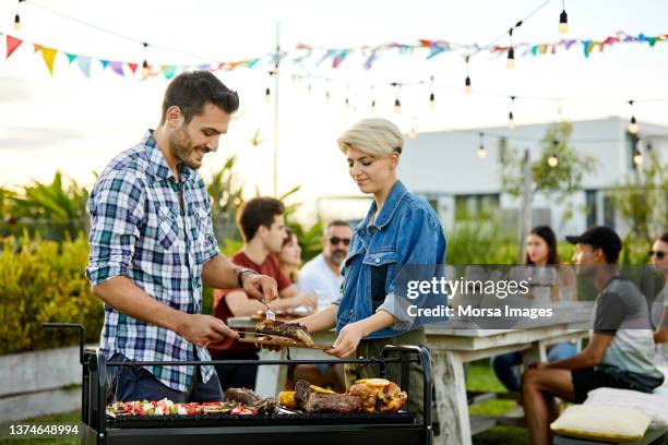 man serving meat prepared on grill during asado - grill party stockfoto's en -beelden