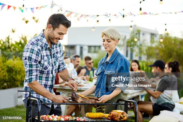 male serving meat to friend during asado - grill 個照片及圖片檔