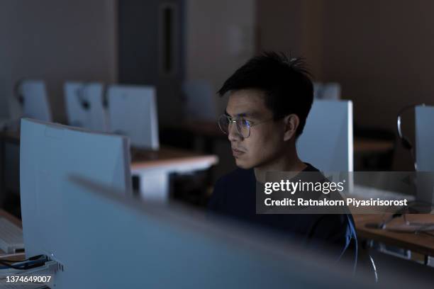 young adult asian man working late at night in their office with desktop computer. using as hard working and working late concept. programmer and hacker concept - work hard play hard stock pictures, royalty-free photos & images