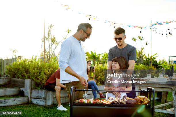 happy people by barbecue grill in backyard - backyard barbecue stock-fotos und bilder