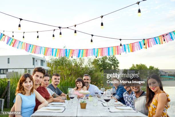 family and friends enjoying in backyard - sitting at table looking at camera stock-fotos und bilder