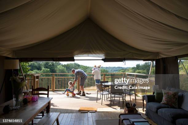 family playing on sunny deck outside yurt cabin - luxury tent stock pictures, royalty-free photos & images