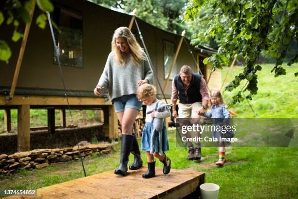 happy family holding hands walking outside cabin in woods - gemeinsam gehen stock-fotos und bilder