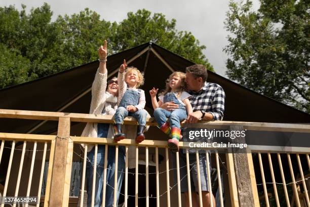 happy family at sunny cabin railing - log cabin stock pictures, royalty-free photos & images