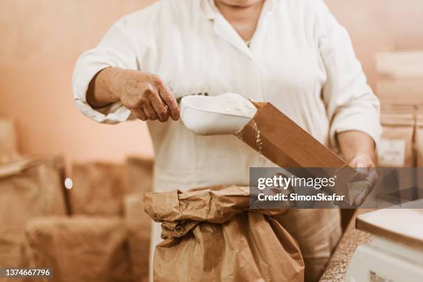 person packing fresh flour in paper bag with scoop - flour bag stockfoto's en -beelden