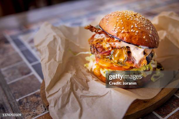 bacon cheeseburger with salad in bun, served on wooden board - sappig stockfoto's en -beelden