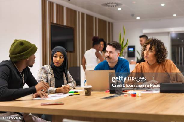 workers talking at common coworking space tables, busy multiethnic businessmen and businesswomen working together in the space of coworking, diverse staff of employees - small business strategy stock pictures, royalty-free photos & images