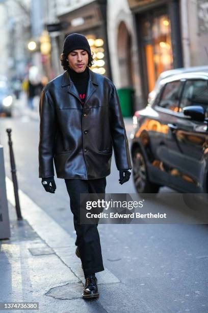 Guest wears a black wool ribbed, a black with red print pattern turtleneck pullover, a black shiny leather jacket, black gloves from The North Face,...