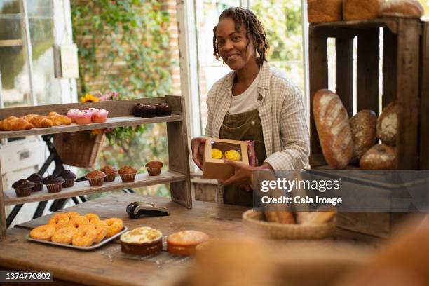 portrait proud female baker boxing pastries in shop - une seule femme d'âge mûr photos et images de collection