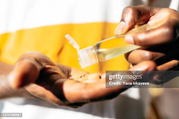 black man is using sanitizing gel, hands close-up - lubricación fotografías e imágenes de stock