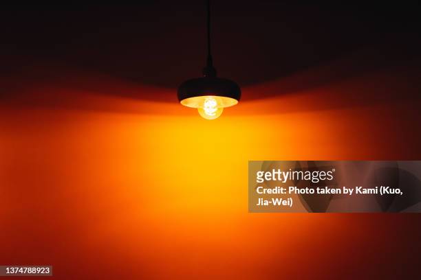 tungsten bulb chandeliers with orange lights scatter on the wall - gloeidraad stockfoto's en -beelden