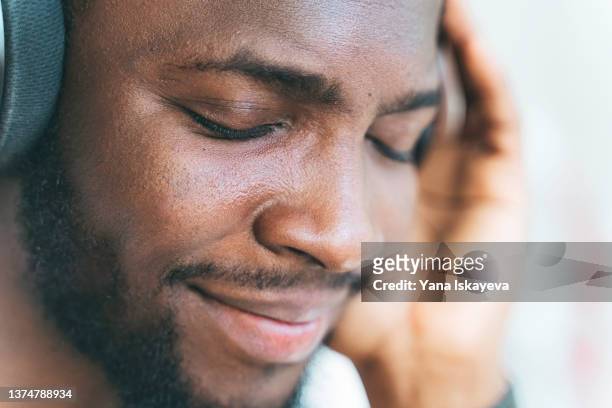 young handsome african-american man is enjoying music in headphones - expressive and music foto e immagini stock
