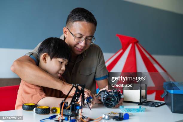 asian father and son building robot toy together at home - real life science stock pictures, royalty-free photos & images