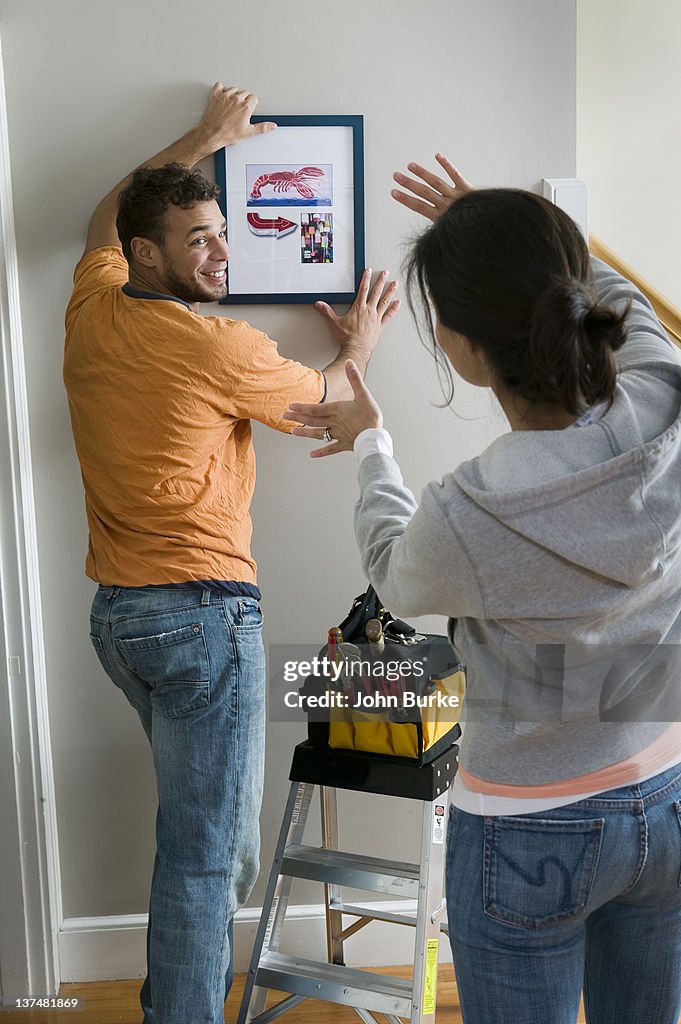 Young couple hanging a picture