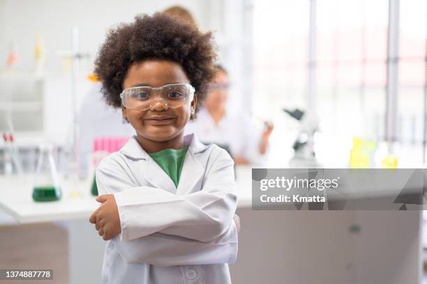 little boy stands confidently in science classroom. - scientifique blouse blanche photos et images de collection