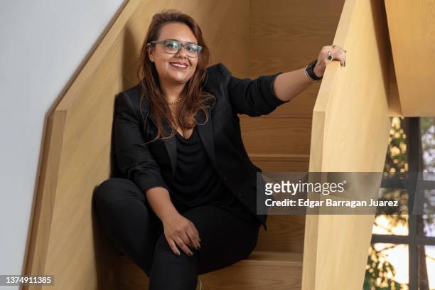 plus size business woman, sitting on the stairs of the office, smiling looking at the camera. - plus size bildbanksfoton och bilder