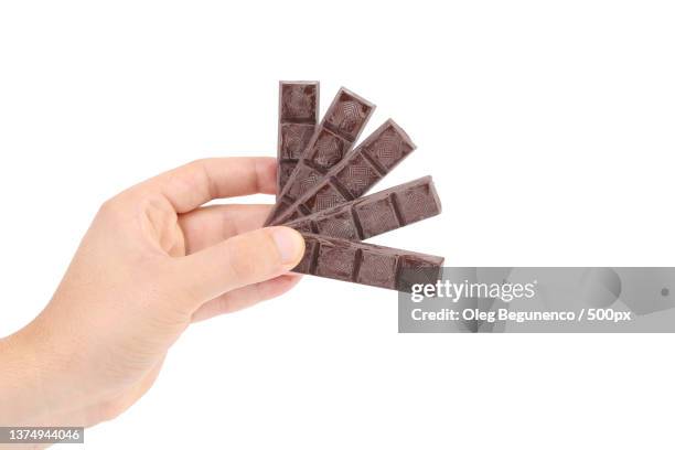 hand holds chocolate bars,cropped hand of woman holding chocolate against white background,moldova - chocolate bar stock pictures, royalty-free photos & images