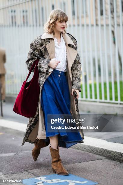 Guest wears a white lace print pattern blouse, a beige and black print pattern oversized long coat, a red wool handbag, brown suede pointed block...