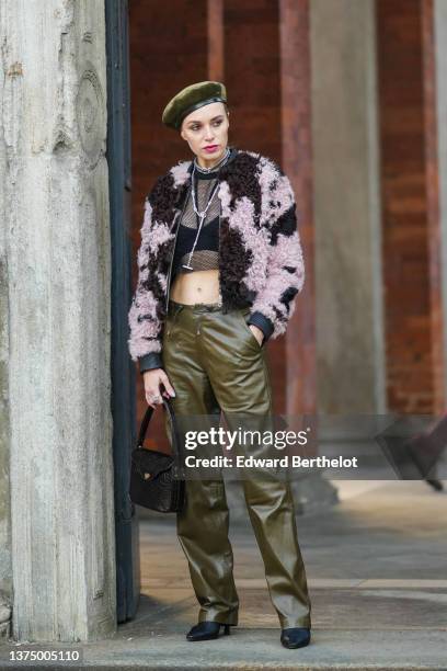 Guest wears a khaki ribbed velvet beret, a silver chain necklace, a black mesh cropped t-shirt, a black V-neck bra underwear, a pale pink and brown...