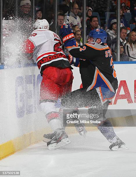 Justin Faulk of the Carolina Hurricanes is checked into the boards by Mark Streit of the New York Islanders at Nassau Veterans Memorial Coliseum on...