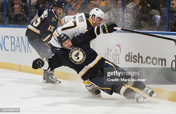 Scott Nichol of the St. Louis Blues slips and slams into the boards as Tyler Myers of the Buffalo Sabres skates after the puck in an NHL game on...