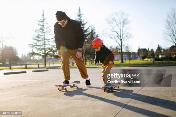vater skateboarding mit seinem sohn - skate stock-fotos und bilder